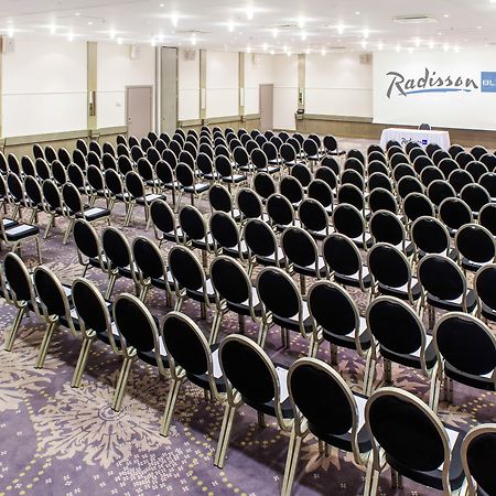 فندق راديسون بلو سكاي تالين المظهر الخارجي الصورة The photo shows a large conference room setup with rows of black chairs arranged facing a stage or presentation area at the front. The room has a light-colored carpet with a decorative pattern and is well-lit, featuring ceiling lights. In the backgro