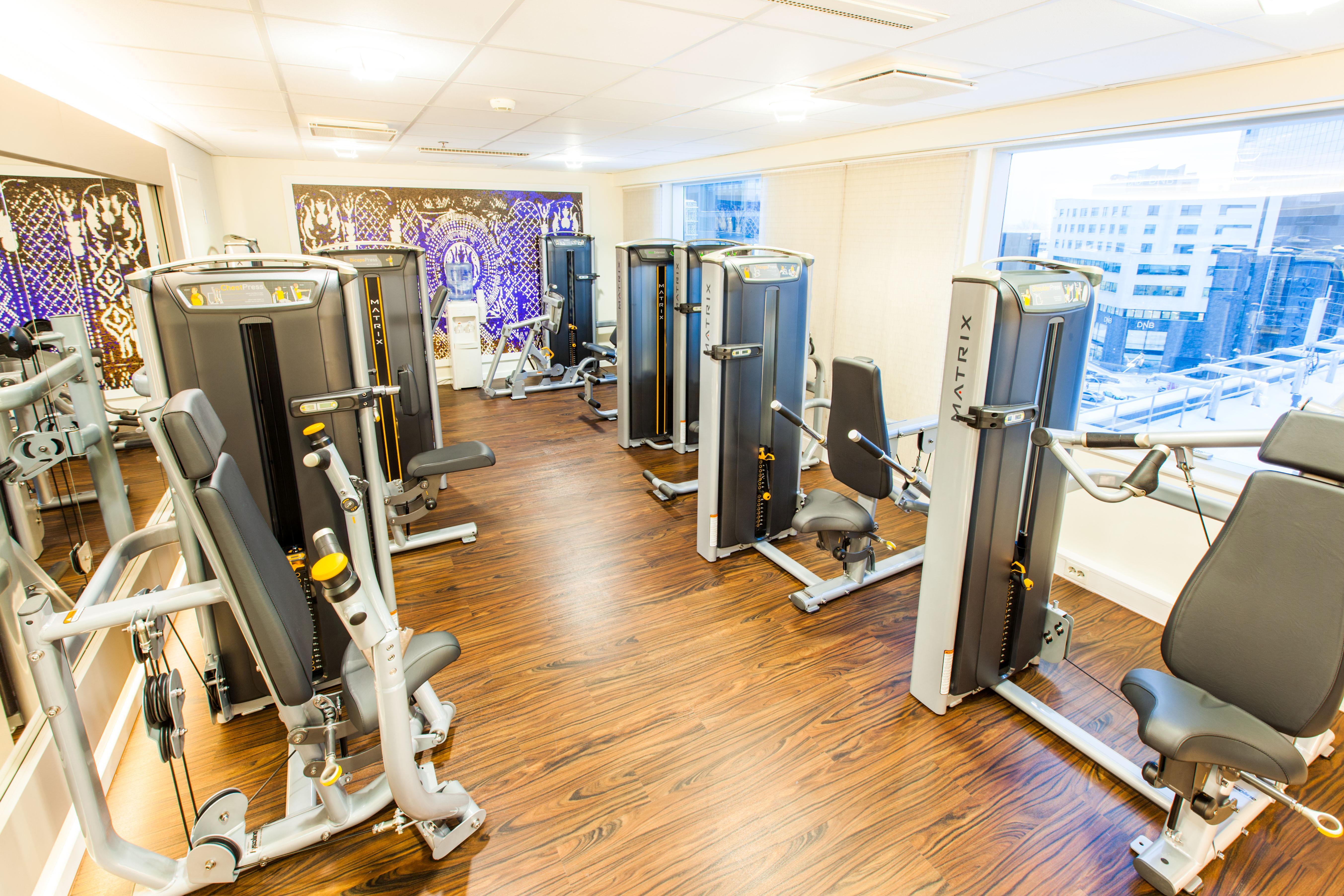 فندق راديسون بلو سكاي تالين المظهر الخارجي الصورة The photo shows a modern fitness room equipped with several gym machines. The space has a wooden floor and large windows that provide natural light and a view of the outside. The equipment appears to be designed for strength training, with various ma
